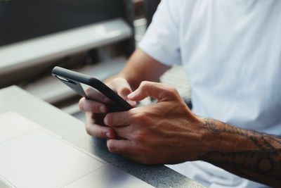 Midsection of man using phone on table at cafe