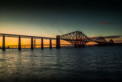 View of suspension bridge over river at sunset