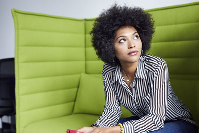 Businesswoman looking away while sitting on sofa in office
