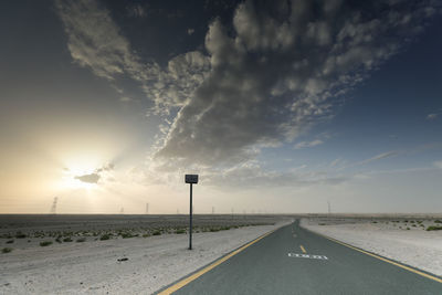 Road by street against sky during sunset