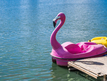 Pink flamingo pedal boat floating on water in lake