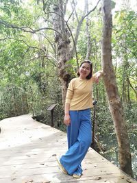 Woman standing on tree trunk against plants