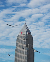 Low angle view of buildings in city against cloudy sky