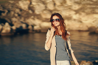 Portrait of smiling young woman wearing sunglasses standing outdoors