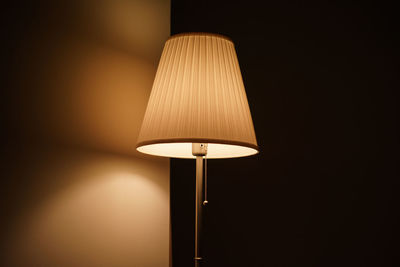 Low angle view of illuminated lamp on wall at home