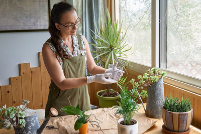 Young woman holding potted plant on table