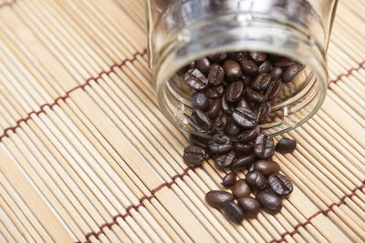 Roasted coffee beans spilling from jar on place mat