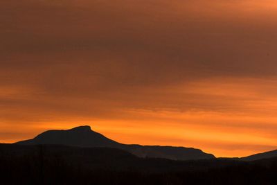 Scenic view of silhouette mountains against orange sky