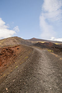 Scenic view of road by mountains against sky