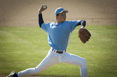Pitcher in light blue and white jersey during wind up on the mound