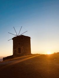 Traditional windmill on field against sky at sunset