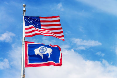 Low angle view of american flag and us state flag against sky