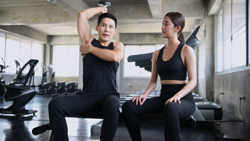 Instructor assisting woman in exercising at gym