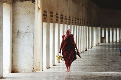 Full length of monk walking in corridor