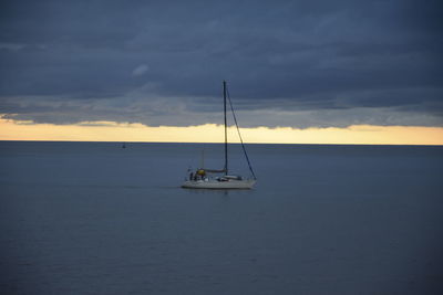 Sailboat sailing on sea against sky during sunset