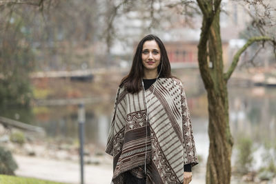 Portrait of smiling young woman standing against trees