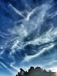 Low angle view of silhouette trees against blue sky