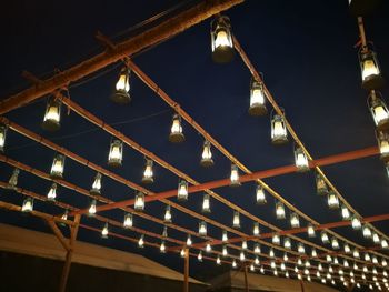 Low angle view of illuminated light bulbs at night