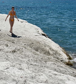 Full length of shirtless man standing on rock at beach