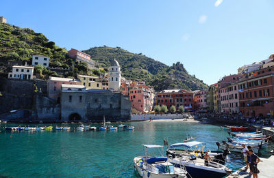 Boats in sea by buildings against sky