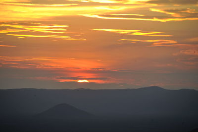 Scenic view of silhouette mountains against orange sky