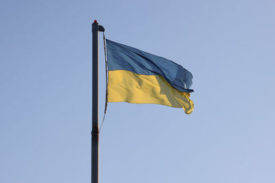 Low angle view of flag against clear blue sky