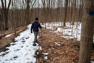 Rear view of senior man hiking on snow covered land