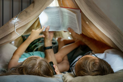Father and son playing and reading in a kid tent at home.