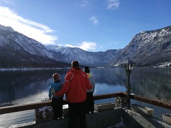 Rear view of father with children looking at lake and mountains against sky
