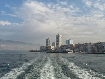 Sea by cityscape against sky