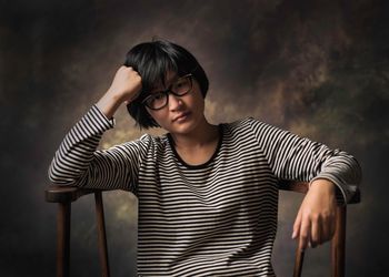 Portrait of depressed boy sitting on chair against wall