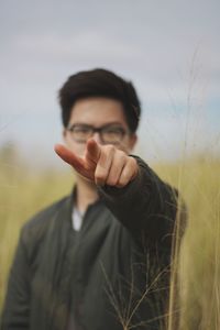 Portrait of young woman pointing while standing on field