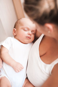 Mother holding sleeping baby at home