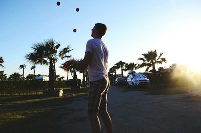 Rear view of man standing on palm tree against sky