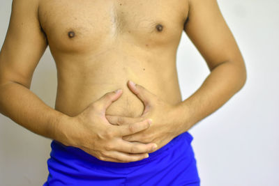 Midsection of shirtless man against white background