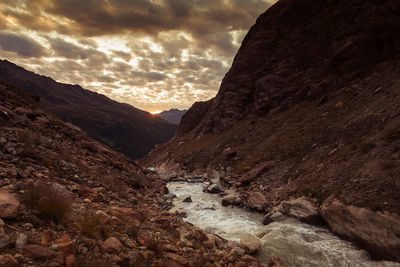 Glacial stream under a dramatic sky at sunset, alto adige, italy