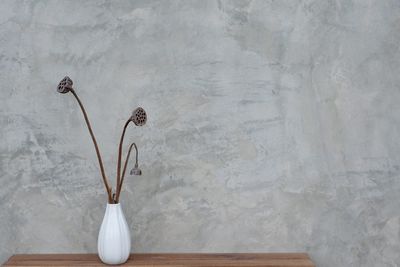 Close-up of white vase on table against wall