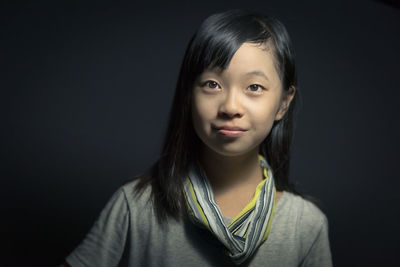 Close-up portrait of girl against black background