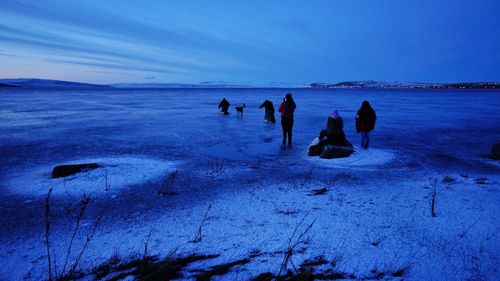 People on frozen sea against sky during winter