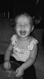 Cute girl with closed eyes eating candies while sitting on floor at home