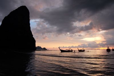 Silhouette boats in sea against sky during sunset