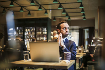 Worried businessman looking away while sitting in restaurant