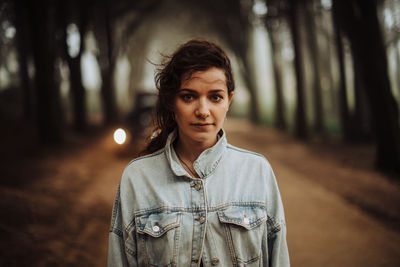 Close up of a young woman with messy hair standing alone in forest