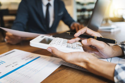 Midsection of man holding mobile phone on table