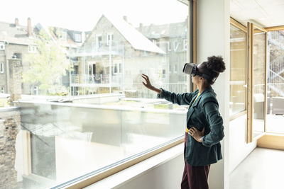 Woman looking at camera while standing by window