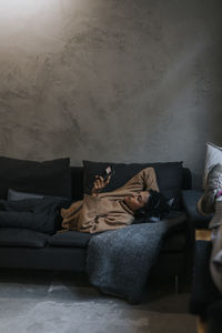 Businesswoman using smart phone while resting on sofa in creative office