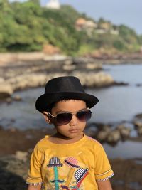 Portrait of boy wearing sunglasses standing at beach during sunny day