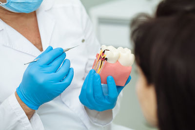 Midsection of dentist explaining tooth model to patient