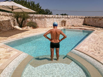 Full length of shirtless man standing in swimming pool