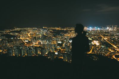 Silhouette person standing against illuminated cityscape at night